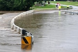 Locals look at water over a flooded road in the New South Wales town of Queanbeyan on March 1, 2012.