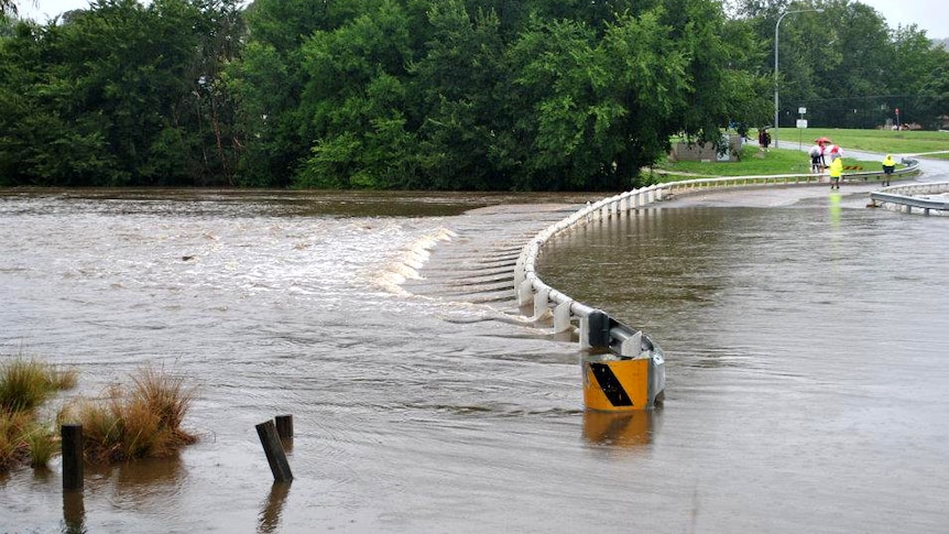 Locals look at water over a flooded road in the New South Wales town of Queanbeyan on March 1, 2012.