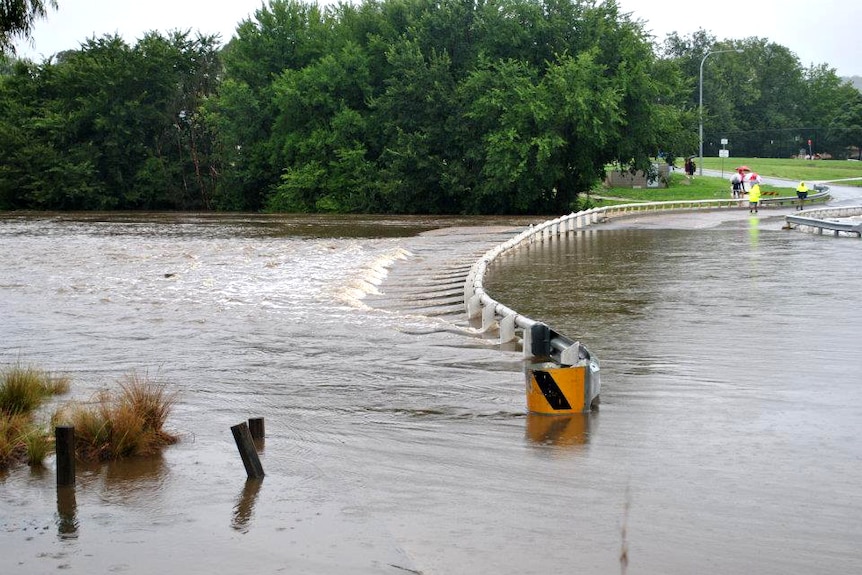 Locals look at water over a flooded road in the New South Wales town of Queanbeyan on March 1, 2012.
