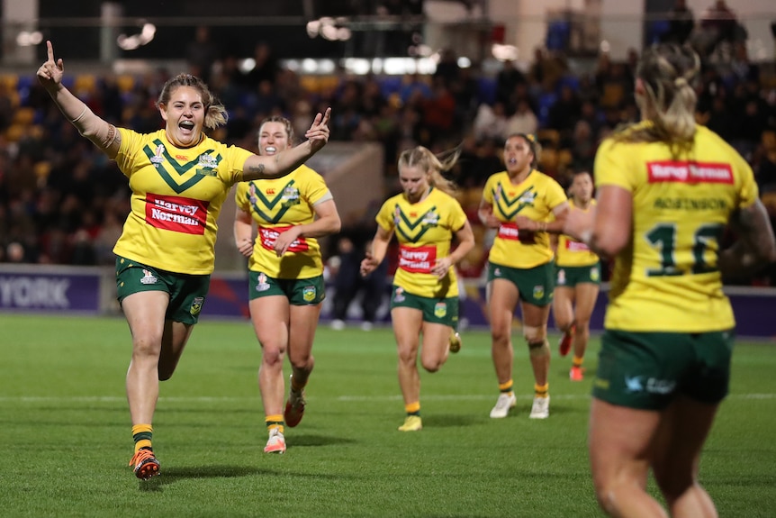 Caitlan Johnston runs to celebrate a try with Australian Jillaroos teammate Julia Robinson at the Rugby League World Cup.