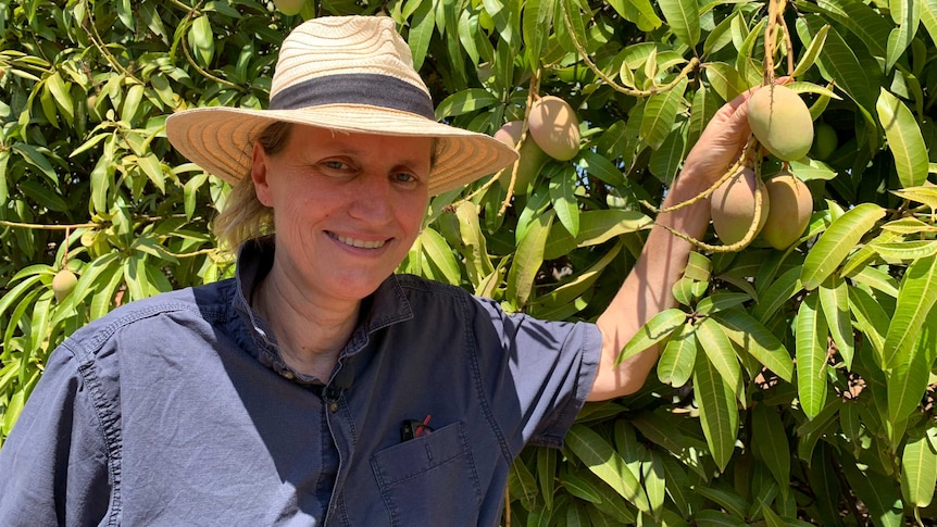 Martina Matzner stands next to a mango tree.