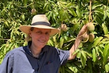 Martina Matzner stands next to a mango tree.