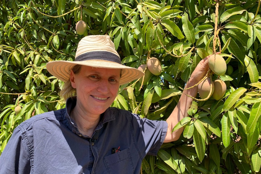 Martina Matzner stands next to a mango tree.