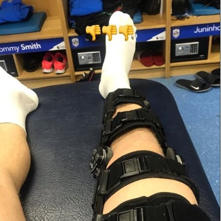 A photo of a right leg encased in a black brace surrounding the knee with three thumbs down emojis
