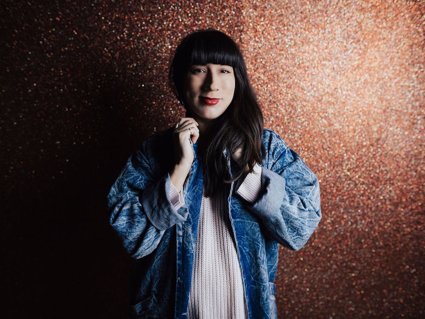 A woman looking at the camera with a glittery background