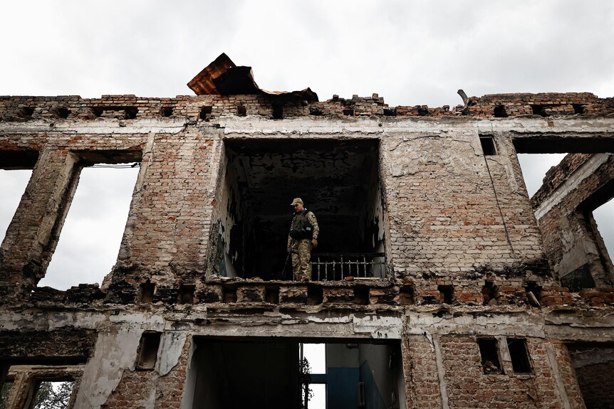 A Ukrainian army officer, stands among the remains of a school that was destroyed during the fighting.