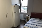 A fridge, cupboard and bed inside a mico apartment in Sydney