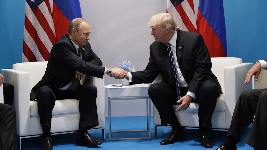 Donald Trump and Vladimir Putin look at each other and smile while shaking hands at the G20 Summit.