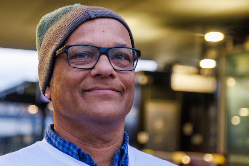 Viresh Ratnayeke smiles, standing outside a train station.