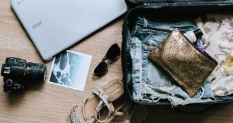 Flat lay of luggage including camera and laptop