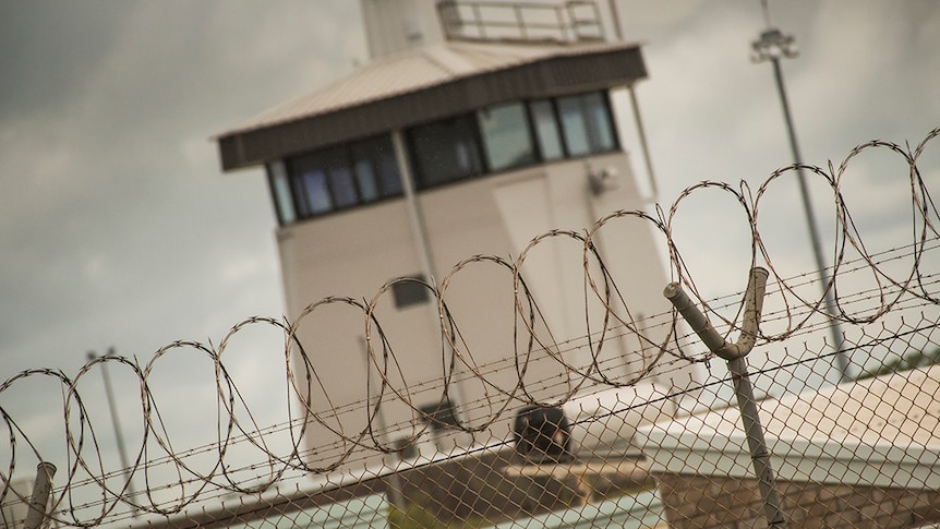 A guard tower behind a barbed wire topped fence.