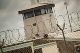 A guard tower behind a barbed wire topped fence.