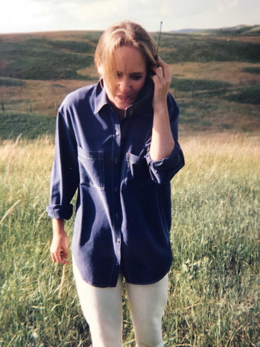 Ferguson holding standing in field talking on early model mobile phone.