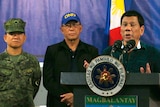 Philippine President Rodrigo Duterte speaks at a lectern, flanked by military personnel.
