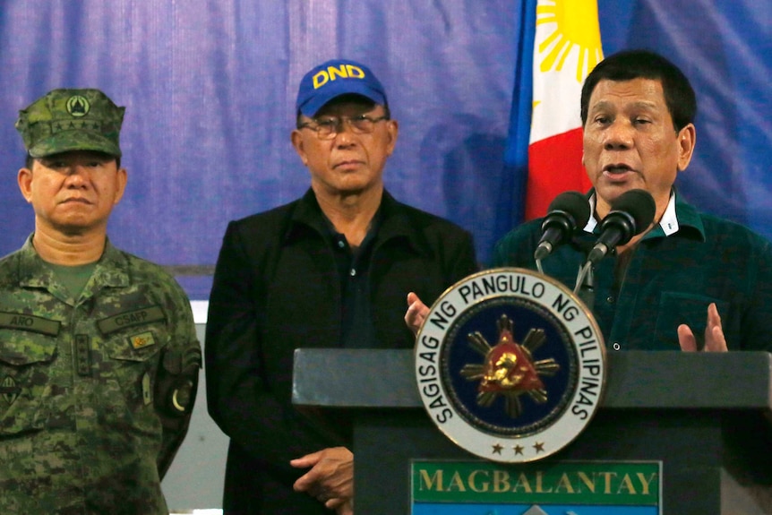 Philippine President Rodrigo Duterte speaks at a lectern, flanked by military personnel.