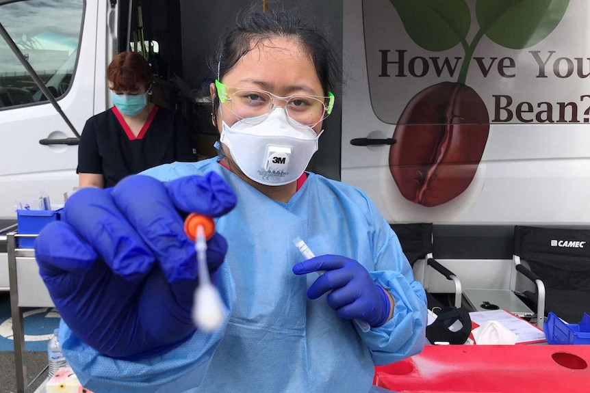 Health worker holds a swab for a test for COVID-19 at drive-through testing clinic.