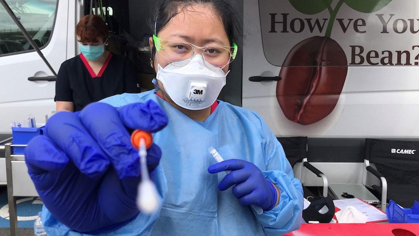 Health worker holds a swab for a test for COVID-19 at drive-through testing clinic.