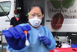 Health worker holds a swab for a test for COVID-19 at drive-through testing clinic.