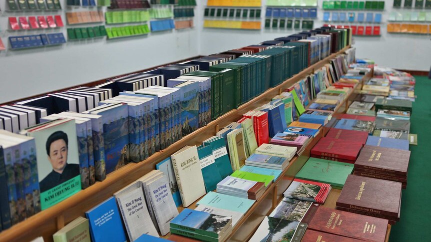 A dimly-lit bookstore has a table of books in a range of colours, albeit penned by only two authors: Kim Il-sung & Kim Jong-Il