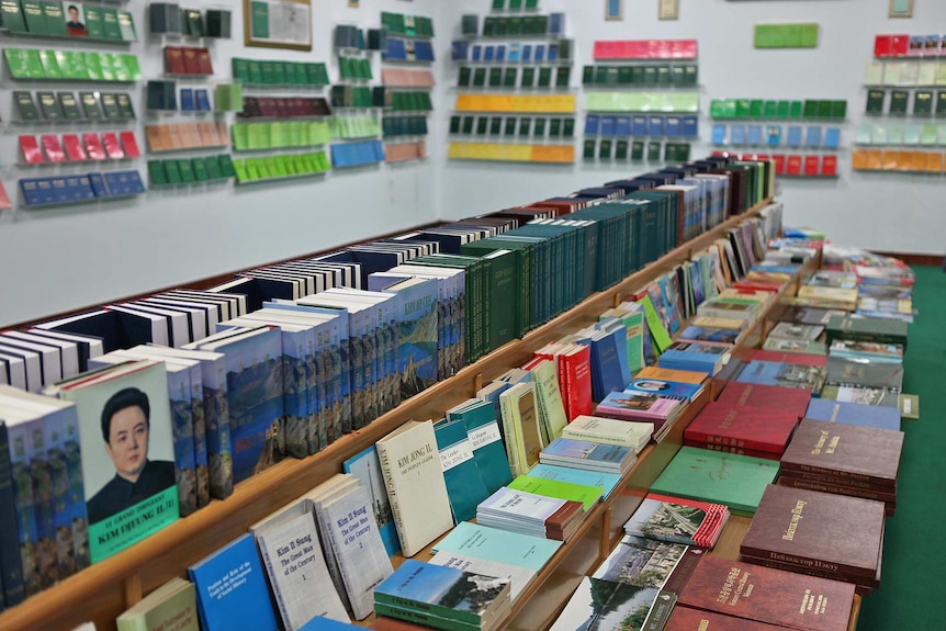A dimly-lit bookstore has a table of books in a range of colours, albeit penned by only two authors: Kim Il-sung & Kim Jong-Il