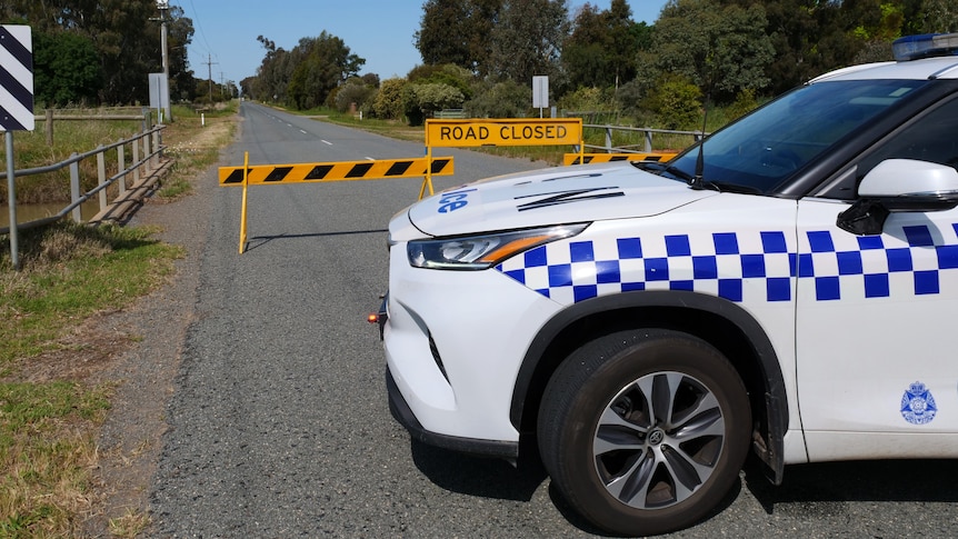 A police car parked on Old Dookie Road in Shepparton in front of a road closed sign.