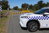 A police car parked on Old Dookie Road in Shepparton in front of a road closed sign.