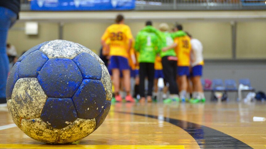 A small, grippy ball used in handball sits on the court.