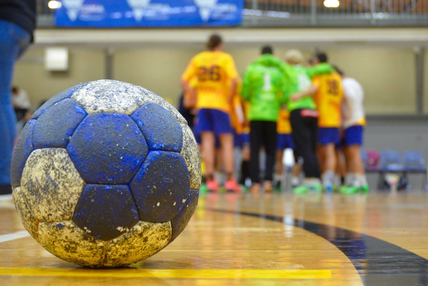 A small, grippy ball used in handball sits on the court.