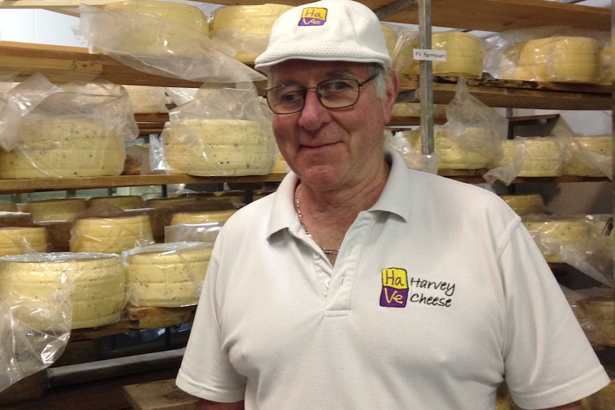 Owner of Harvey Cheese and head cheesemaker Robert St. Duke stands in front of shelves loaded with parmesan cheese.