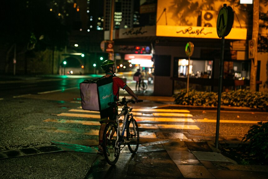 A man with his at a street corner at night