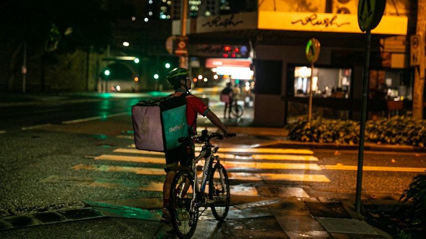 a man with his at a street corner at night