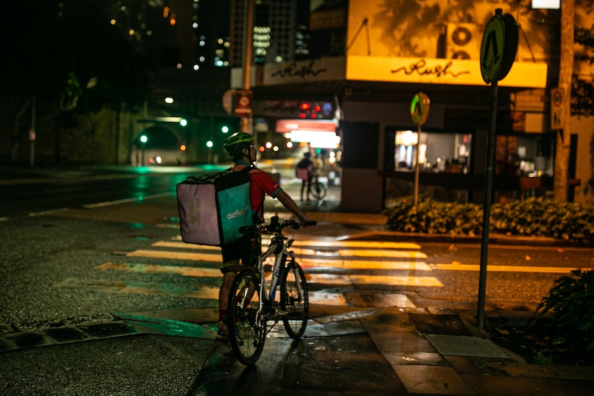 A man with his at a street corner at night