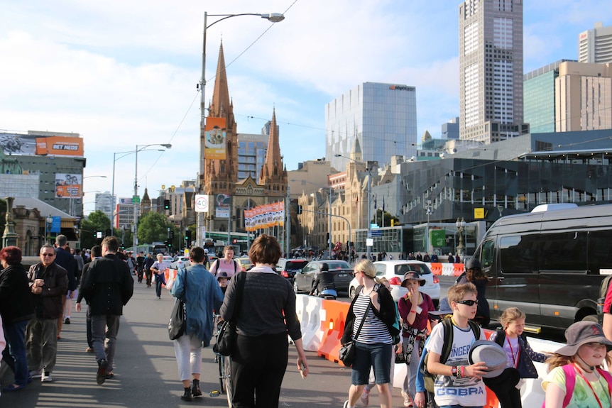 Pedestrians walk along Princes Bridge, near Flinders St Station.