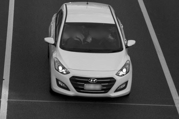 A white car captured on camera travelling on a road.