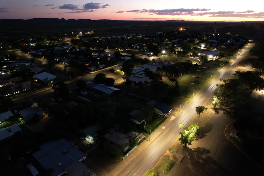 A wide drone shot of streets in a rural town at night.