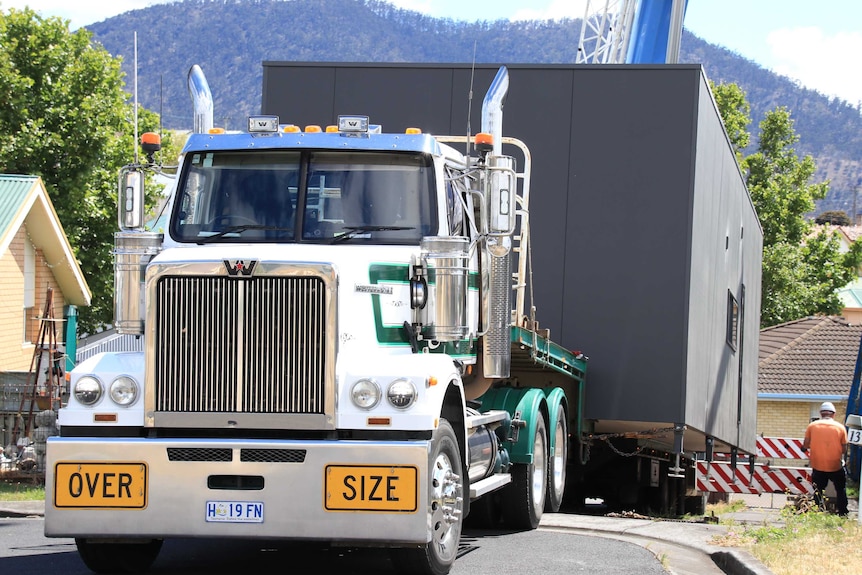 A pod sits on the back of a truck in a suburban street.