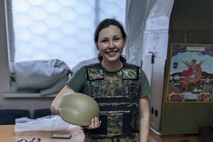 Woman wearing military uniform, holding a helmet.