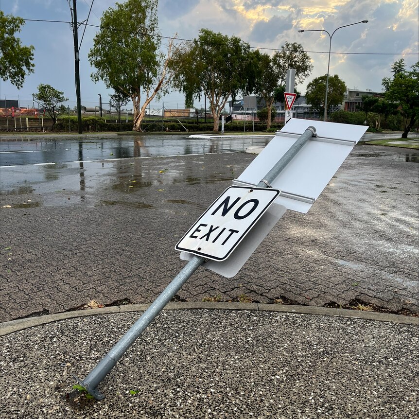 A signpost is pushed over, leaning towards the ground