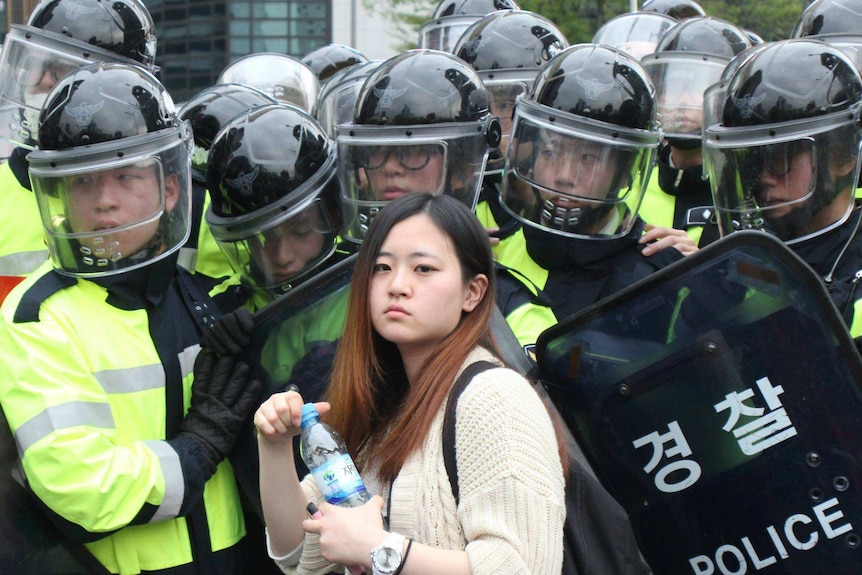 A woman stands in front of police at a protest calling for more action over the Sewol tragedy. April 18, 2015