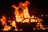 A car is engulfed by flames at night