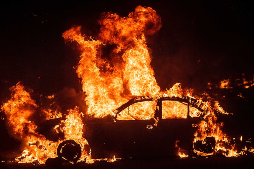 A car is engulfed by flames at night