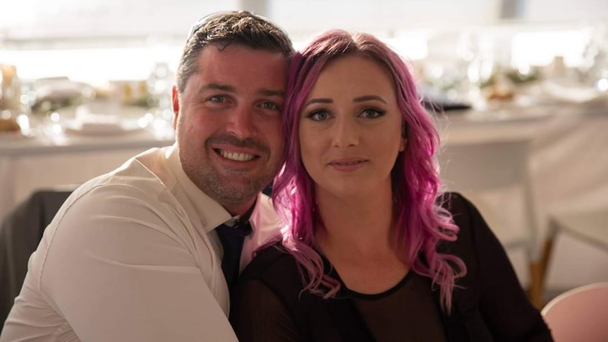 A man and a woman in an embrace smiling towards the camera.