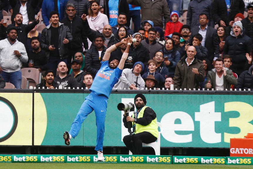 Jasprit Bumrah bobbles the cricket ball as the crowd watches on in anticipation.