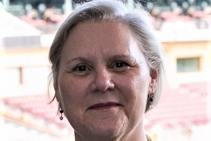 A woman with greying hair and dark lipstick smiles at the camera.