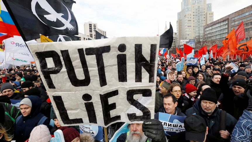 Protesters hold up signs, including one which reads 'Putin lies'
