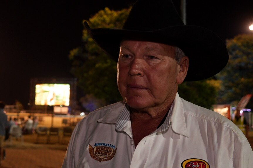 a councillor at an evening festival wearing a black cowboy hat