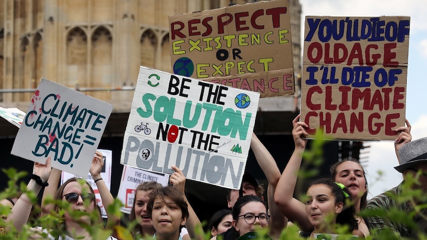 Climate change demonstrators hold placards during a march outside the Houses of Parliament in London.