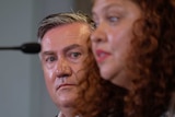 Eddie McGuire looks out from behind Jodie Sizer as she speaks at a press conference