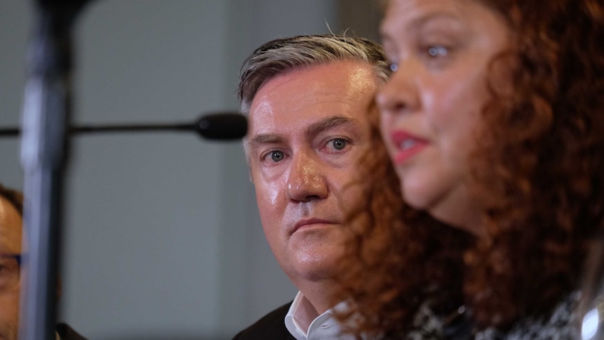 Eddie McGuire looks out from behind Jodie Sizer as she speaks at a press conference