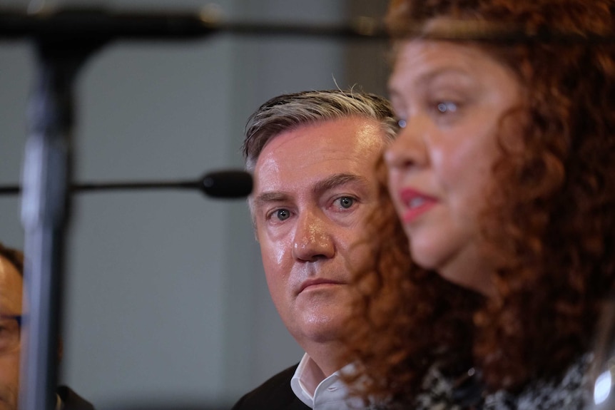 Eddie McGuire looks out from behind Jodie Sizer as she speaks at a press conference